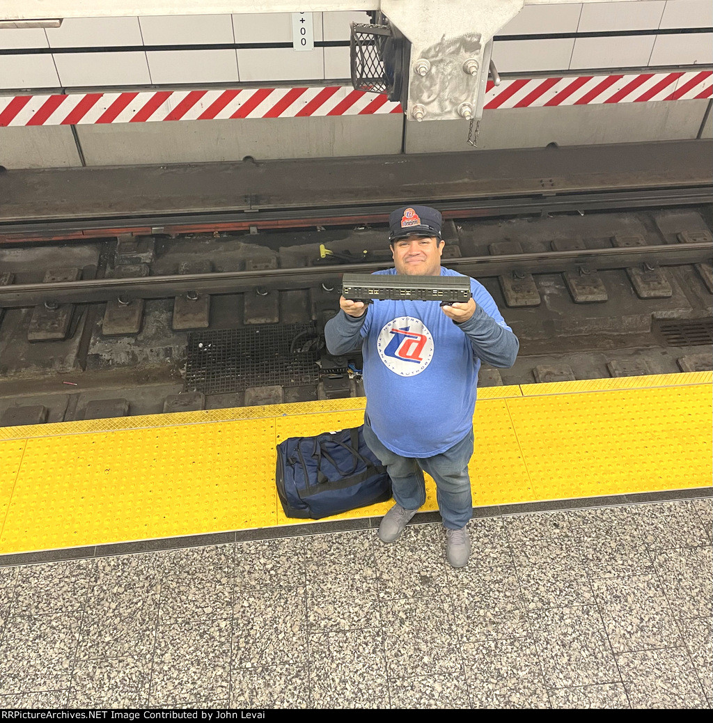 A subway fan holding up a model of an Arnine train while waiting for the real Arnine Set at 96th St Station